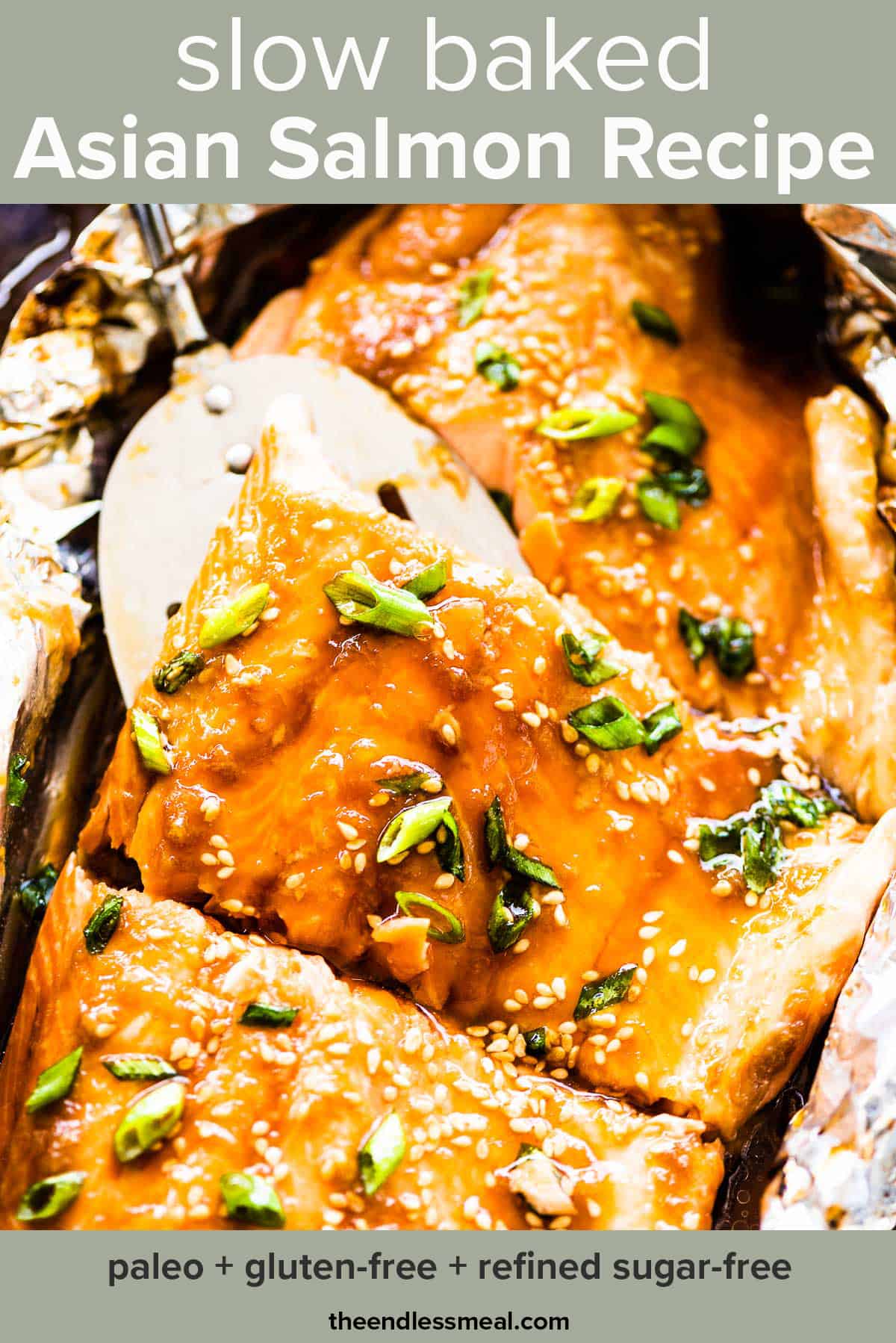 Glazed Asian salmon in foil on a baking sheet with a spatula lifting a piece of salmon and the recipe title on top of the picture.