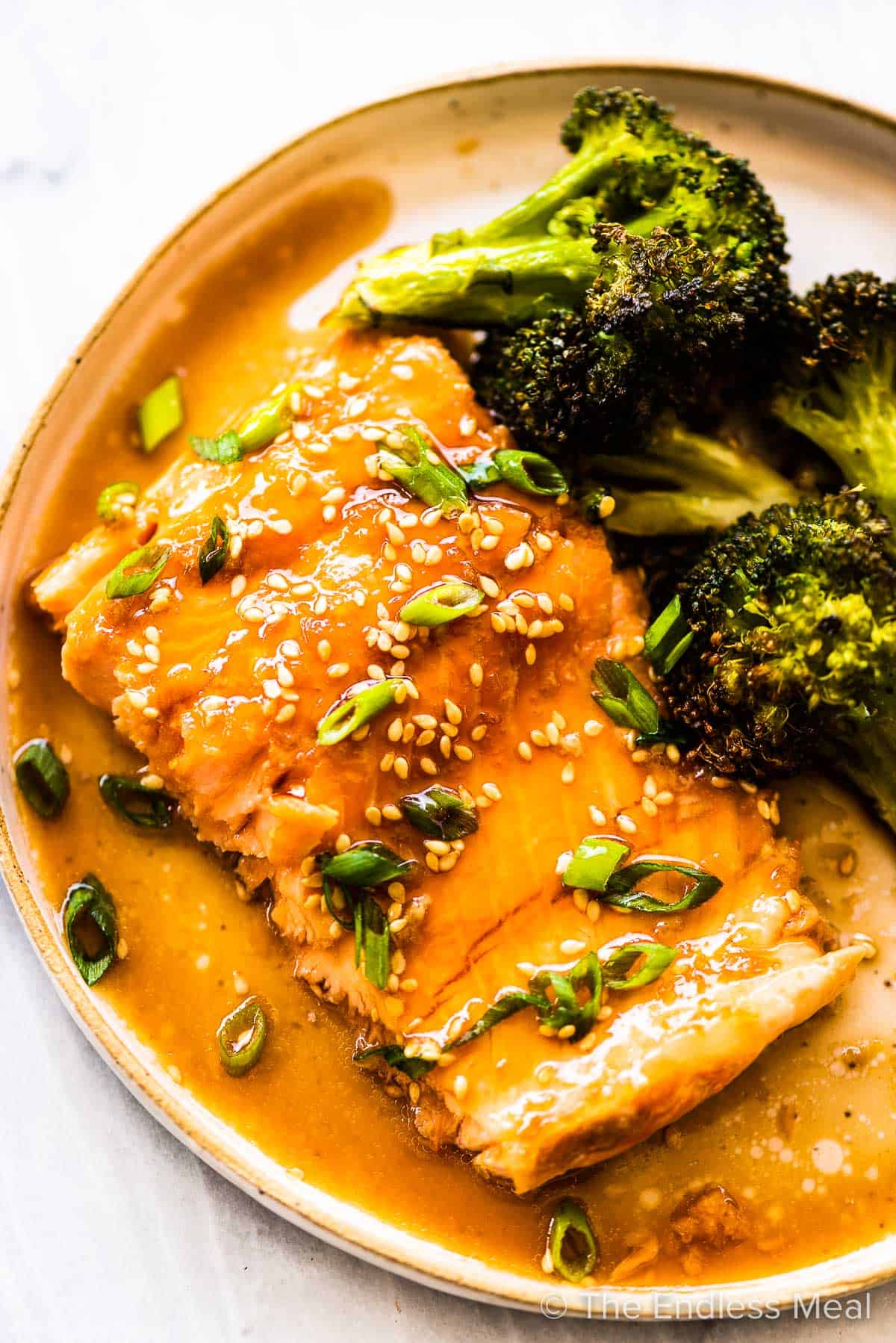 Glazed Asian salmon in a dinner plate with broccoli on the side/