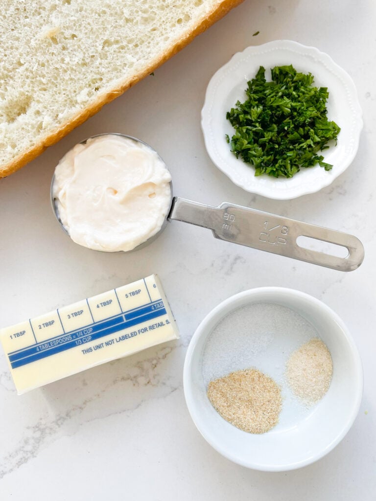 ingredients needed to make a garlic bread spread - fresh parsley, mayo, butter, salt, garlic powder and onion powder