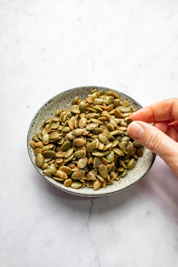 hand holding roasted pepita in bowl