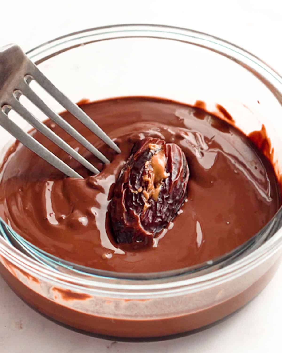 stuffed dates in a bowl of melted chocolate.
