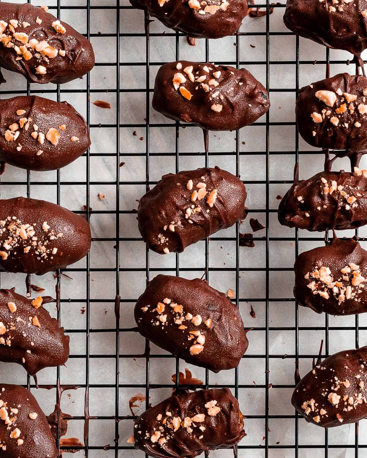 chocolate dates with crushed nuts as a topping on a cooling rack.