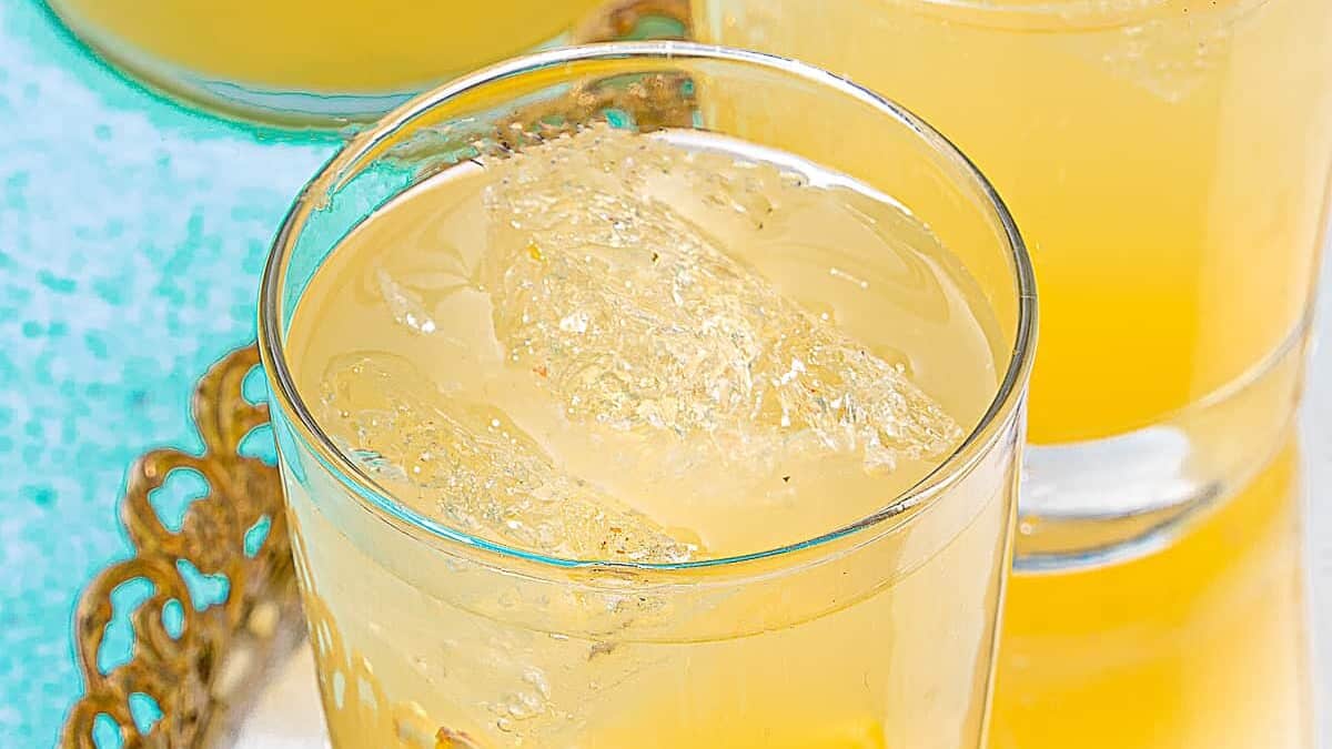 two cocktail glasses with ice and lemon juice on a blue background