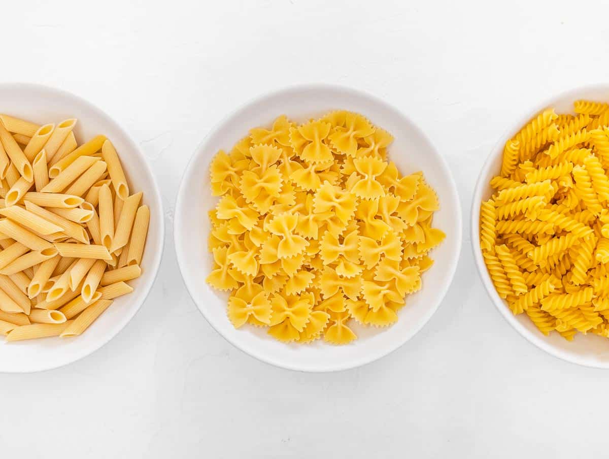 penne, farfalle, and fusilli uncooked in bowls