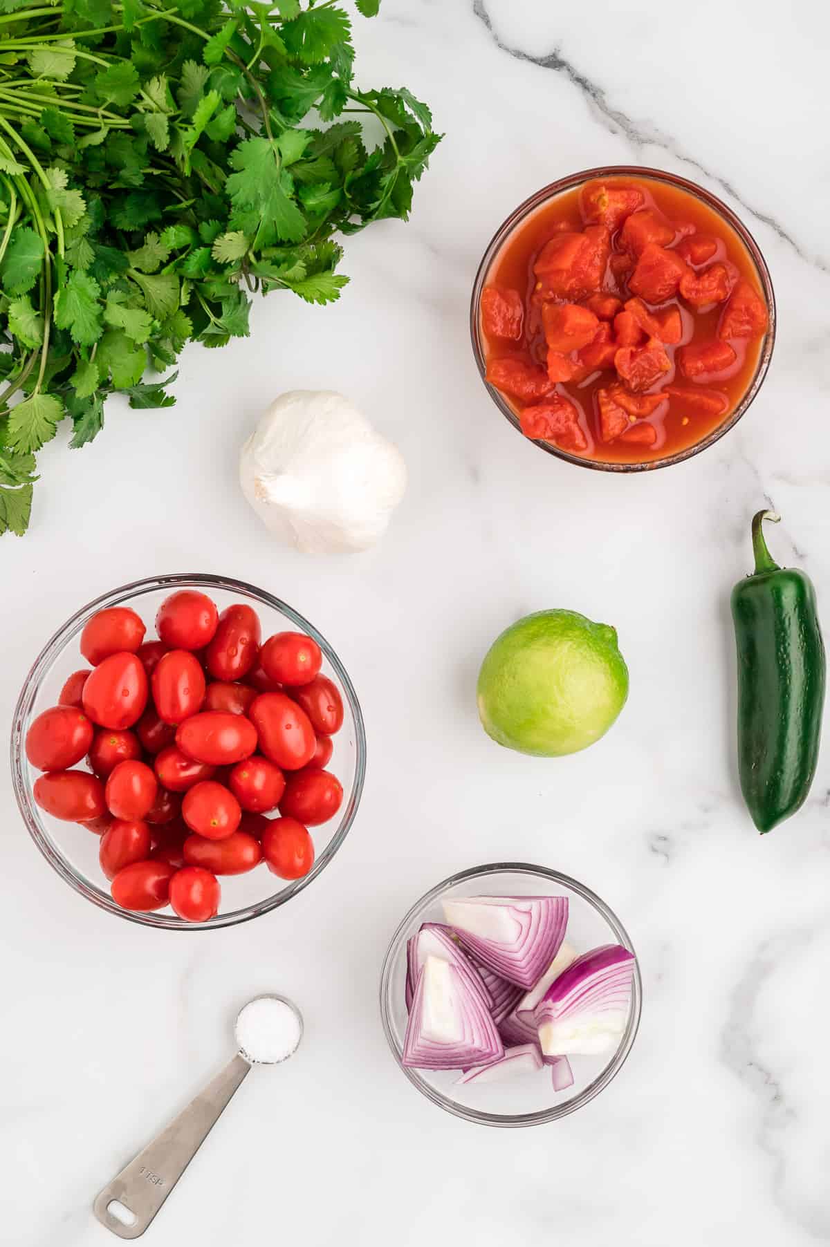 Ingredients for cherry tomato salsa on a marble background.
