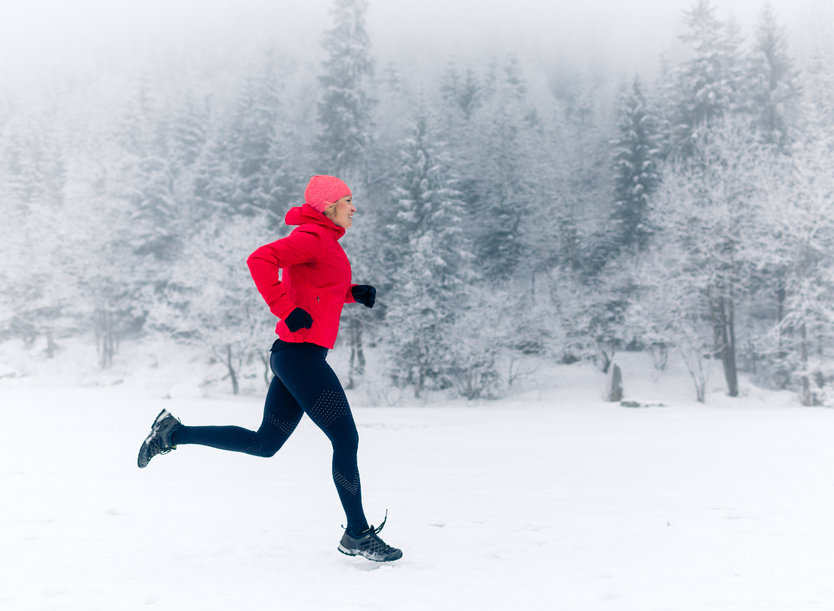 fitness woman running in the snow, demonstrating how to stay fit in the cold