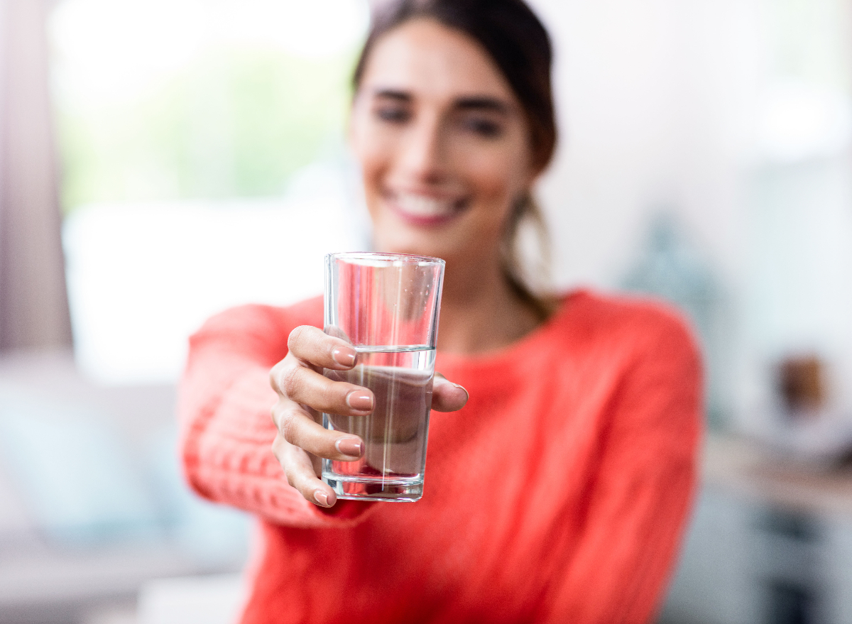 woman holding water glass hydration concept to avoid weight gain