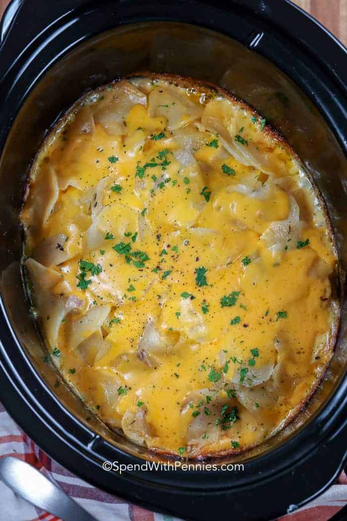 Cheesy Crock Pot scalloped potatoes ready to serve covered in fresh parsley and pepper.