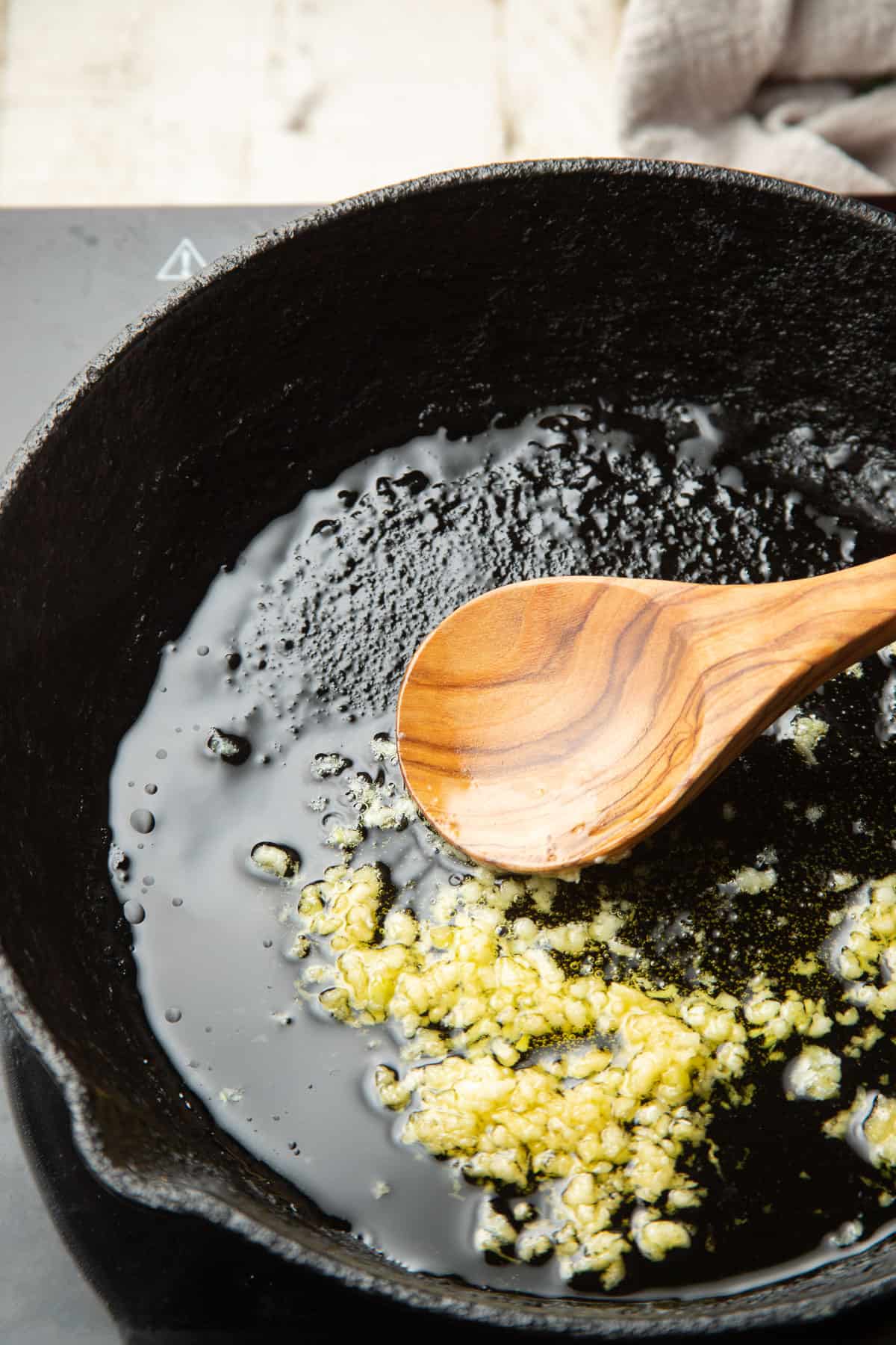 Minced garlic cooking in a skillet with olive oil.