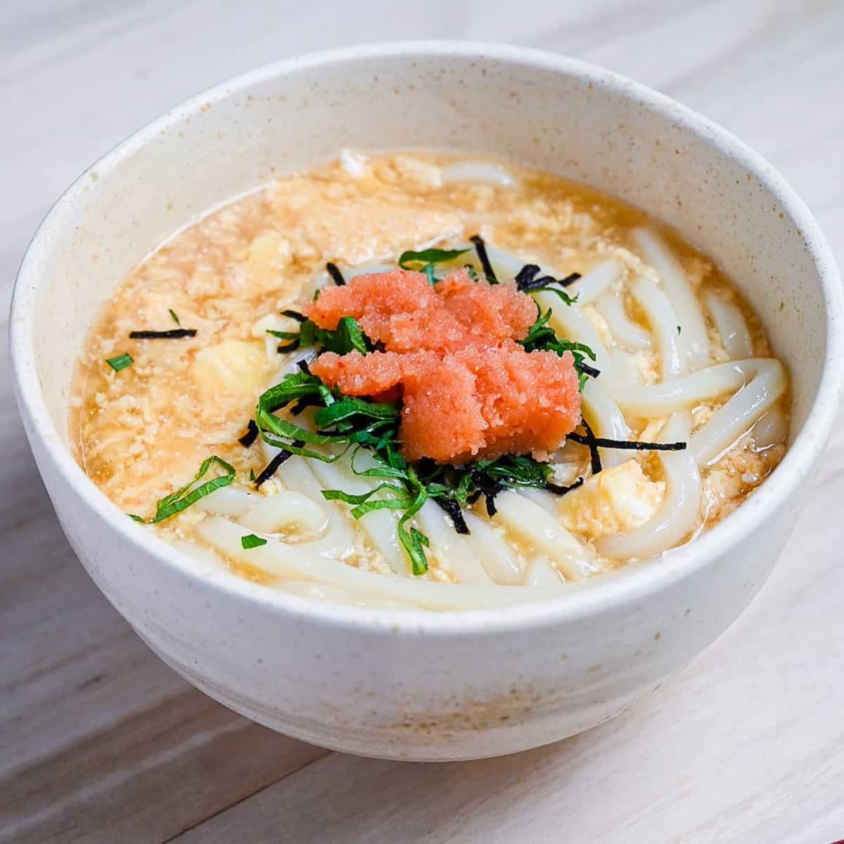 Mentaiko ankake udon served in a cream bowl and topped with shiso leaves. featured image