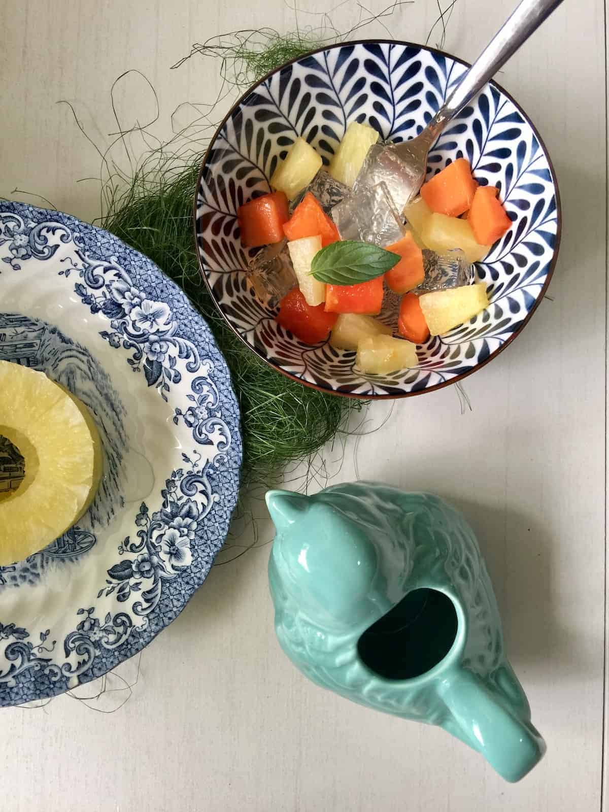 A bowl of fruits and Japanese jelly next to cut pineapple rounds