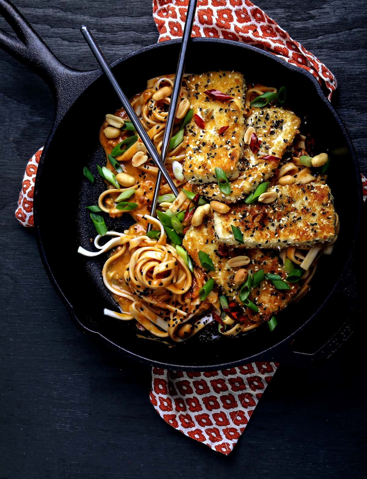 Vegan spicy noodle recipe with crispy tofu in a cast iron pan.