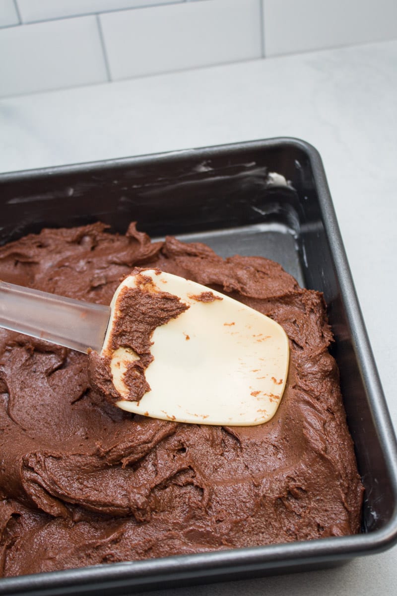 Spreading espresso brownie batter into a prepared baking pan.