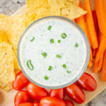 Ranch dip in a bowl garnished with green onions.