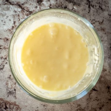 Glass bowl filled with Hollandaise sauce.