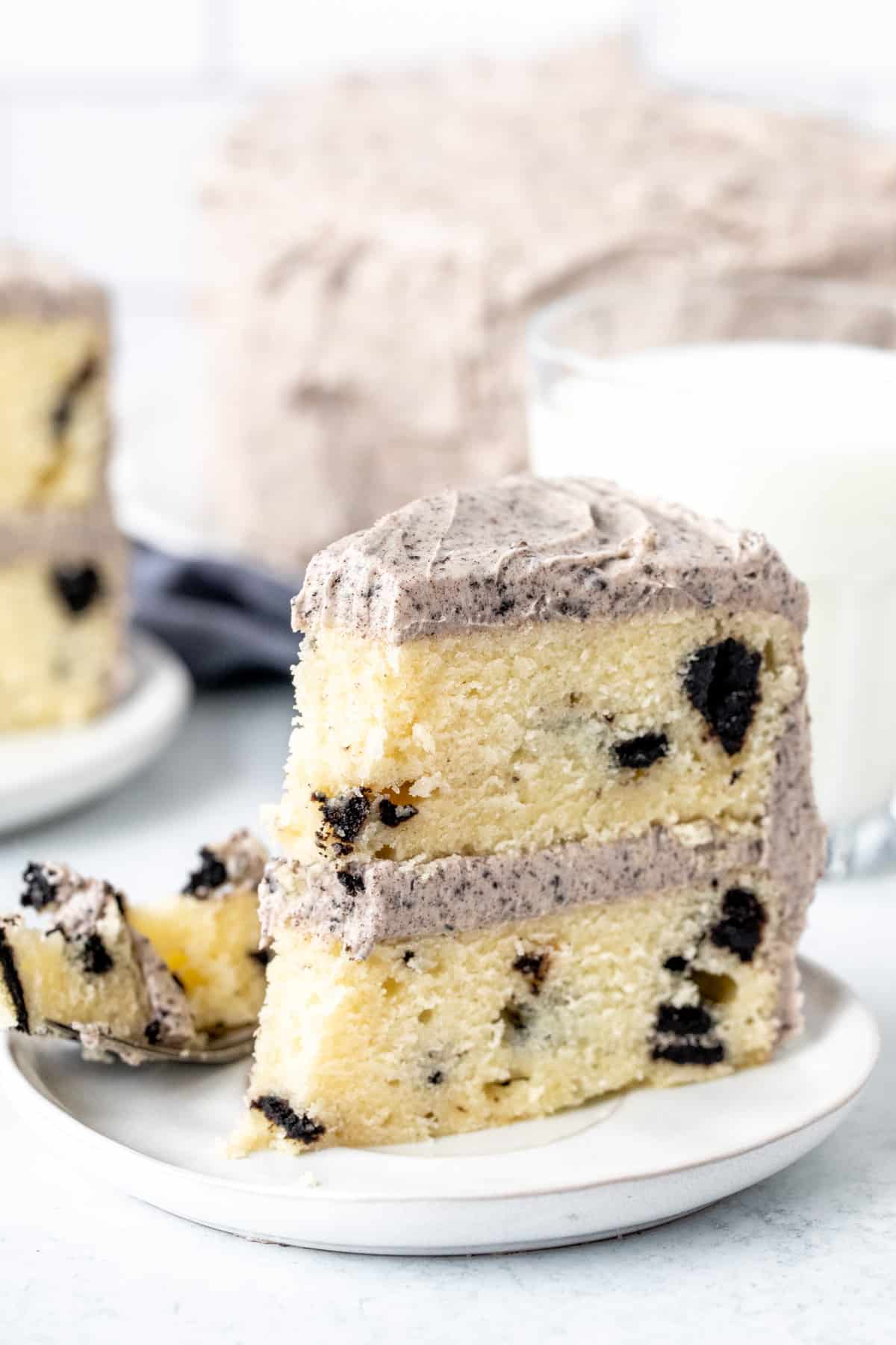 Slice of Oreo cake with a bite taken out of it, with a glass of milk