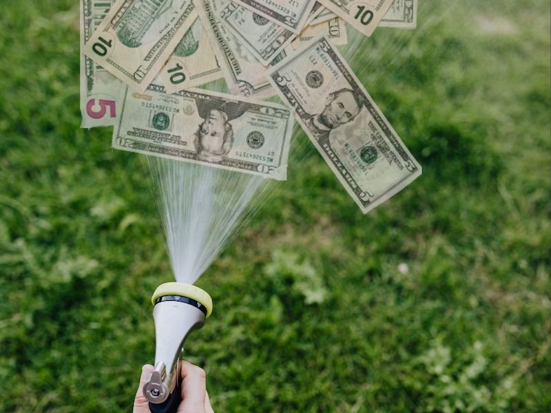 Image showing a hand spraying water with a hose, but money is coming out