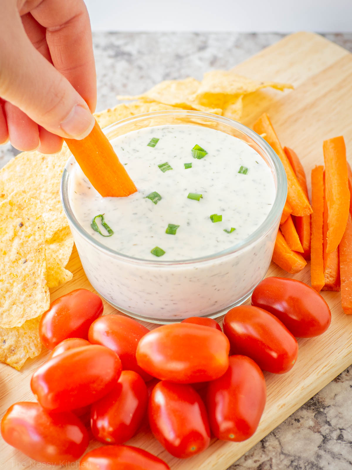Hand dipping a carrot into a bowl of ranch dip.