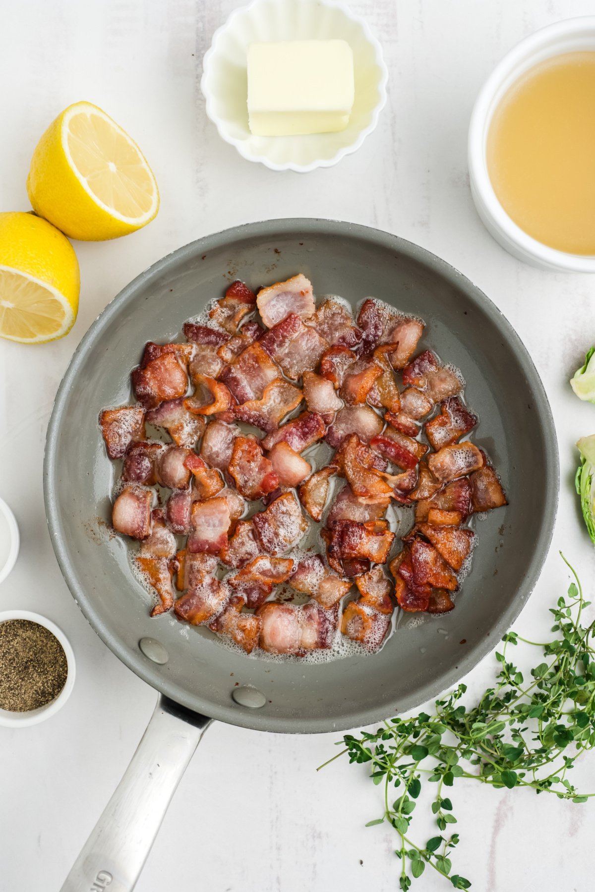 Bacon cooking in a skillet on the table.