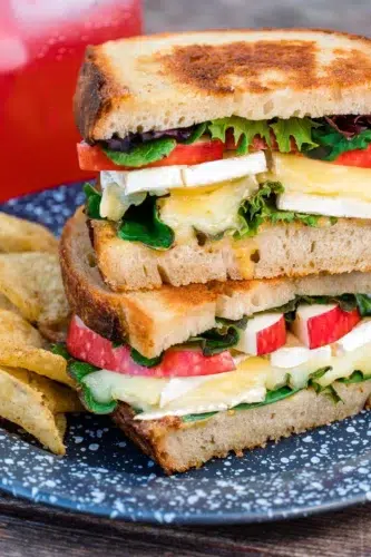 A grilled cheese sandwich is stacked on a plate with chips.