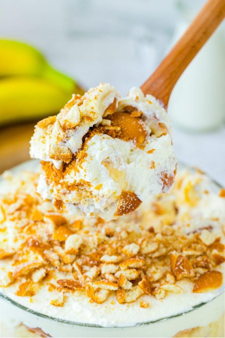 Wooden spoon scooping out the perfect bite of Banana Pudding. The wafers cream and bananas all perfectly come together for the perfect bite.