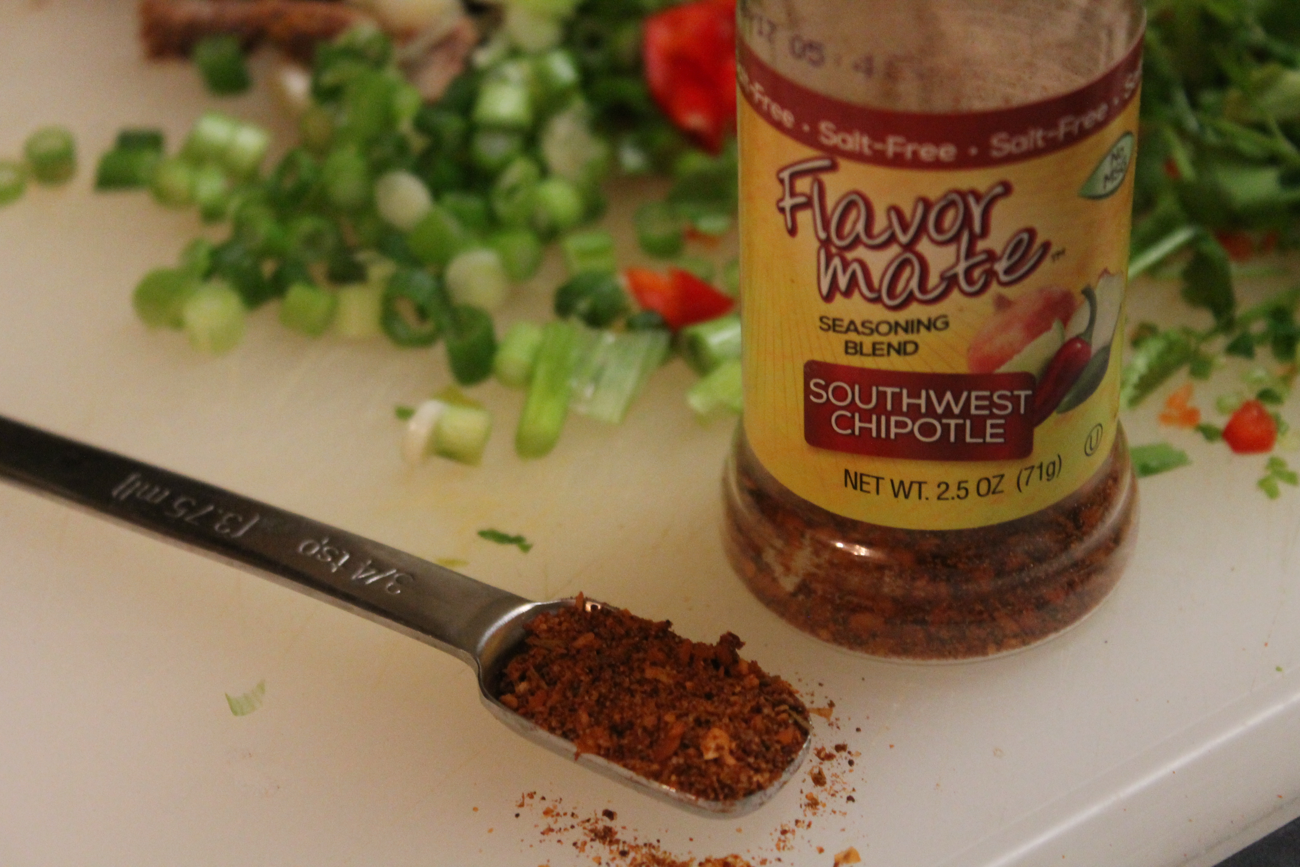 A teaspoon of seasoning sits next to a Flavor Made Southwest Chipotle seasoning bottle—the perfect salt-free seasoning for brisket nachos.