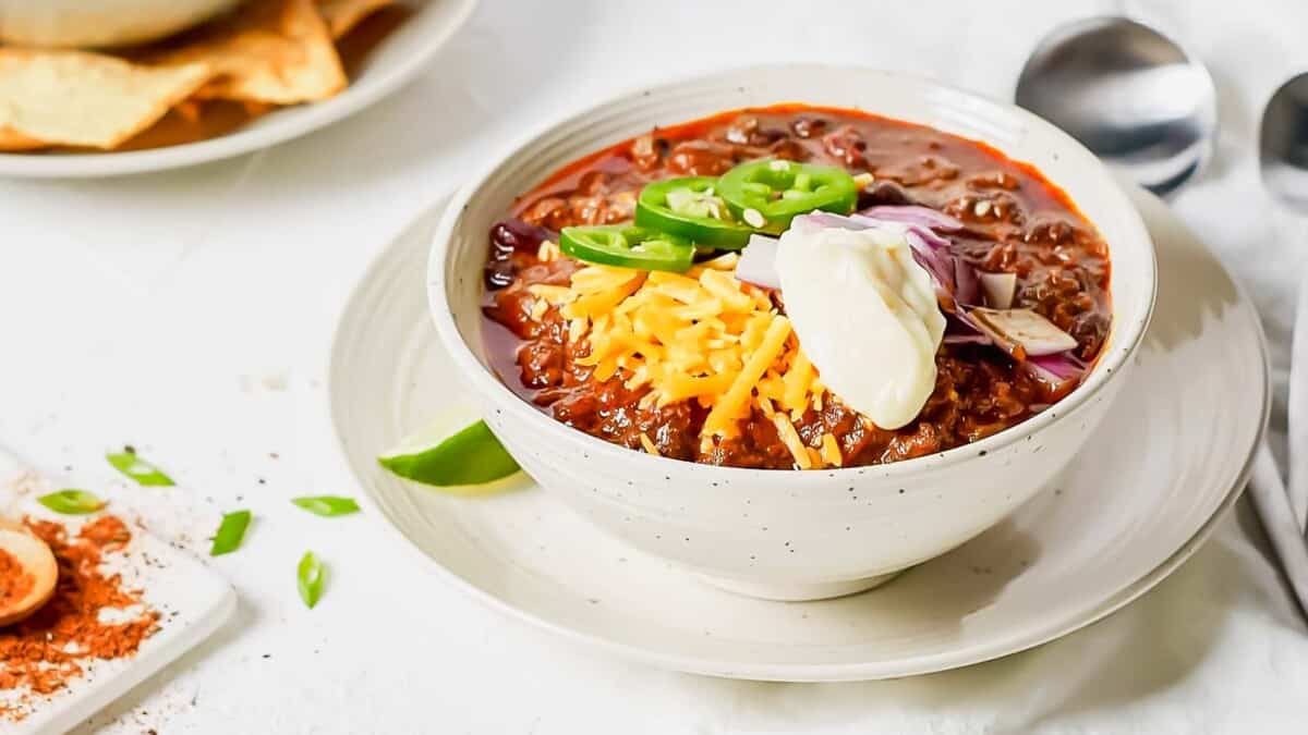 A bowl of chili with cheese and jalapenos.