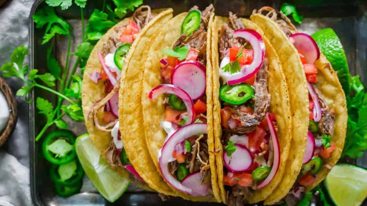 Lamb tacos on a tray with radishes and limes.