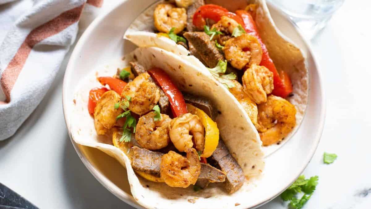 Two fajitas with shrimp and peppers on a plate.