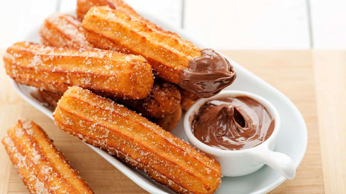 Plate of churros with a side of chocolate dipping sauce.