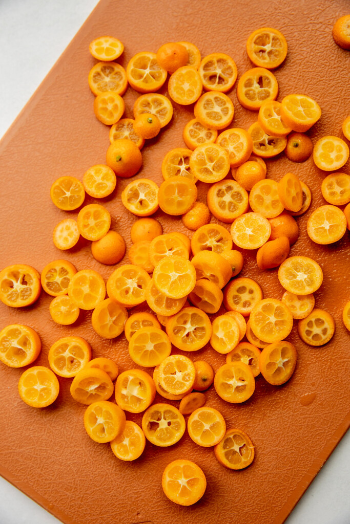 Sliced kumquats on a cutting board.