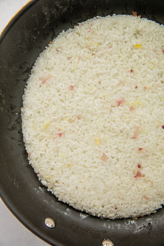 Pressing cooked rice into a circle in a pan.