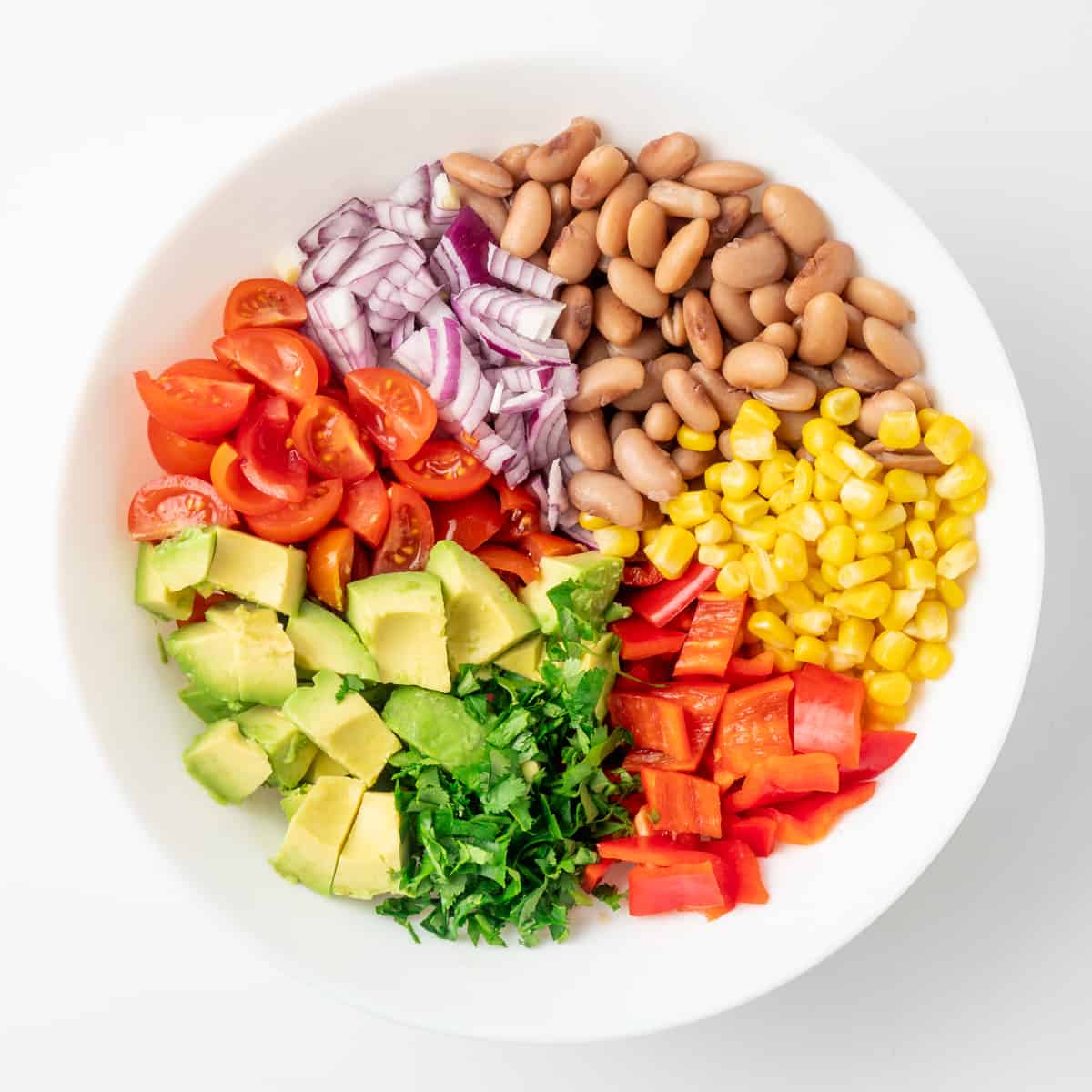 The beans and vegetables making up the bulk of the salad are placed in a salad bowl.