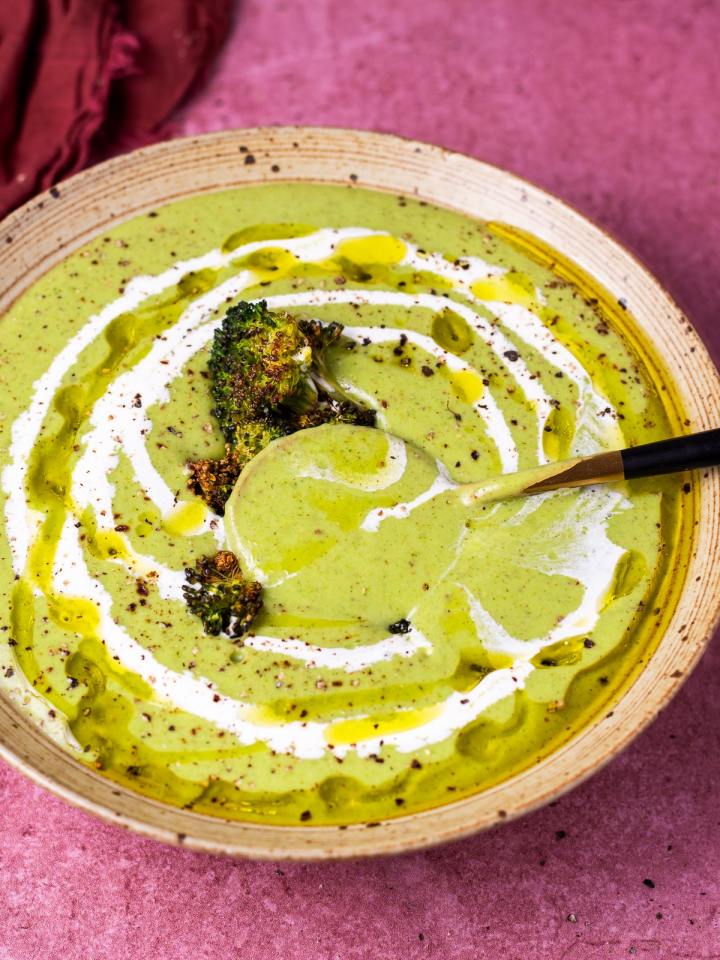 gold spoon dunked in a bowl of creamy broccoli soup