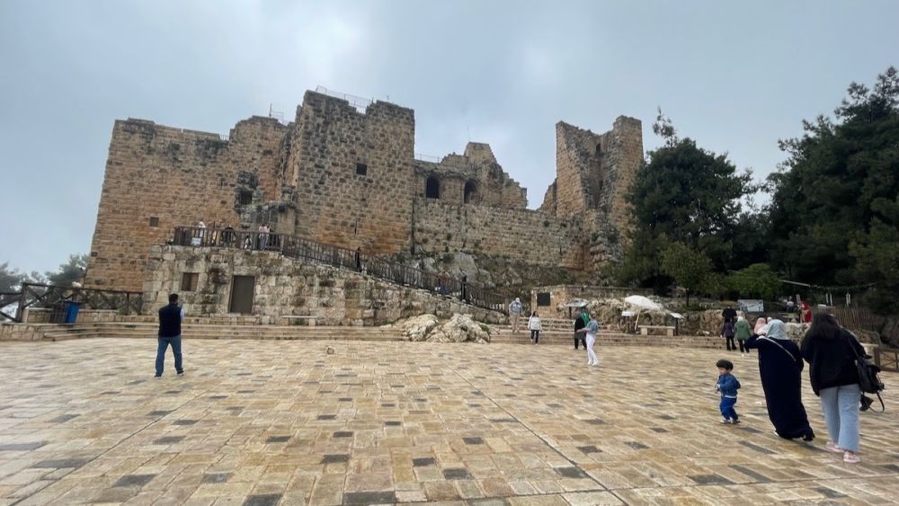 Ruins of a castle as seen across a large plaza.