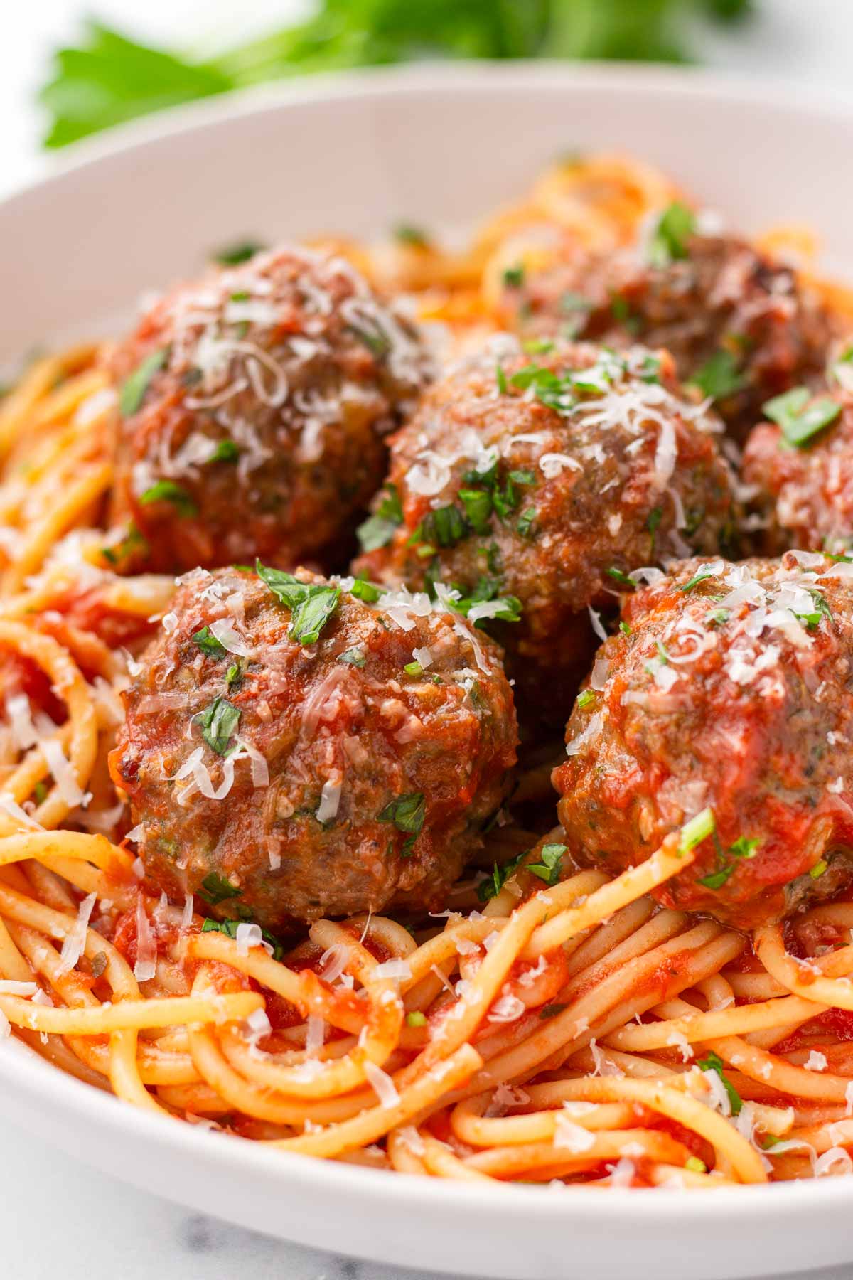 close up of five meatballs on top of saucy spaghetti