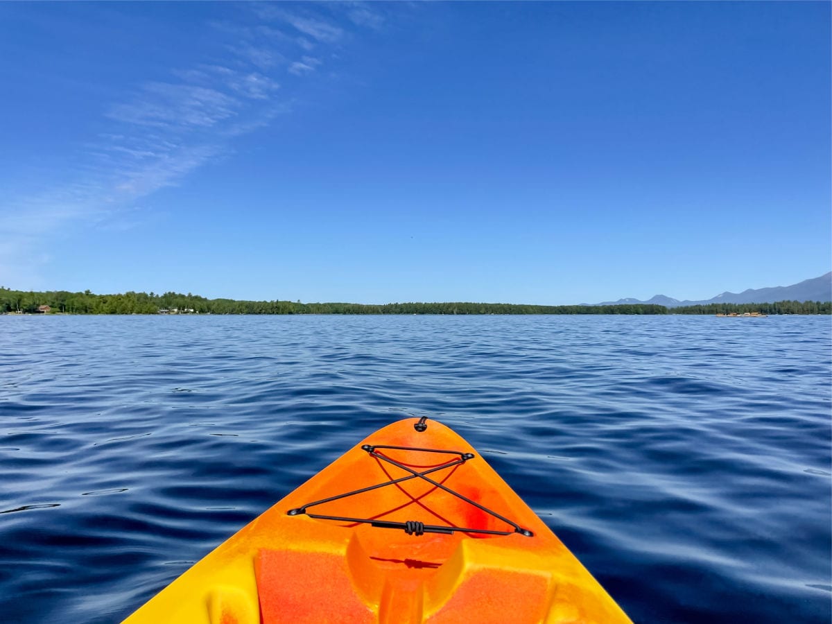 front tip of orange kayak on lake