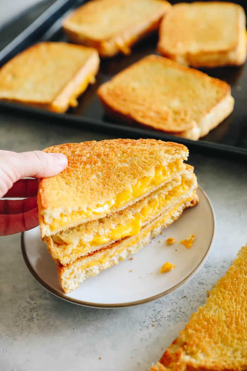 woman's hand picking up sheet pan grilled cheese.