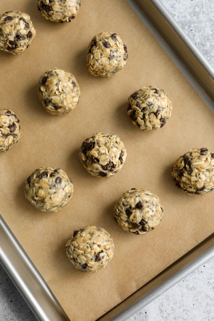Tahini Chocolate Chip Bliss Balls rolled on parchment lined baking sheet