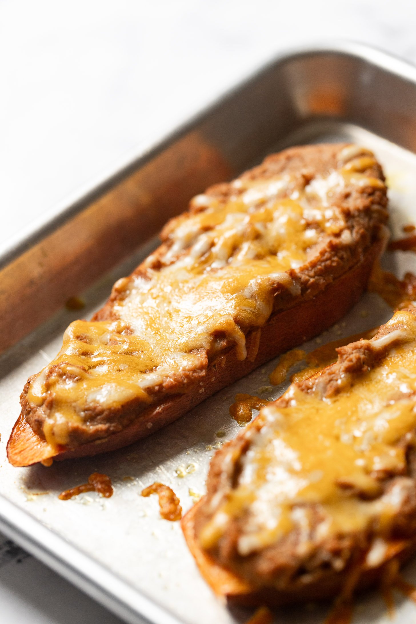 Sweet potato slice with melted cheese on top of beans.