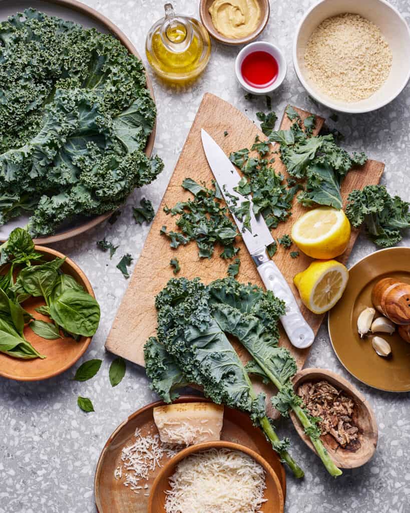 All of the ingredients needed to make this kale salad, laid out on a cutting board on a countertop