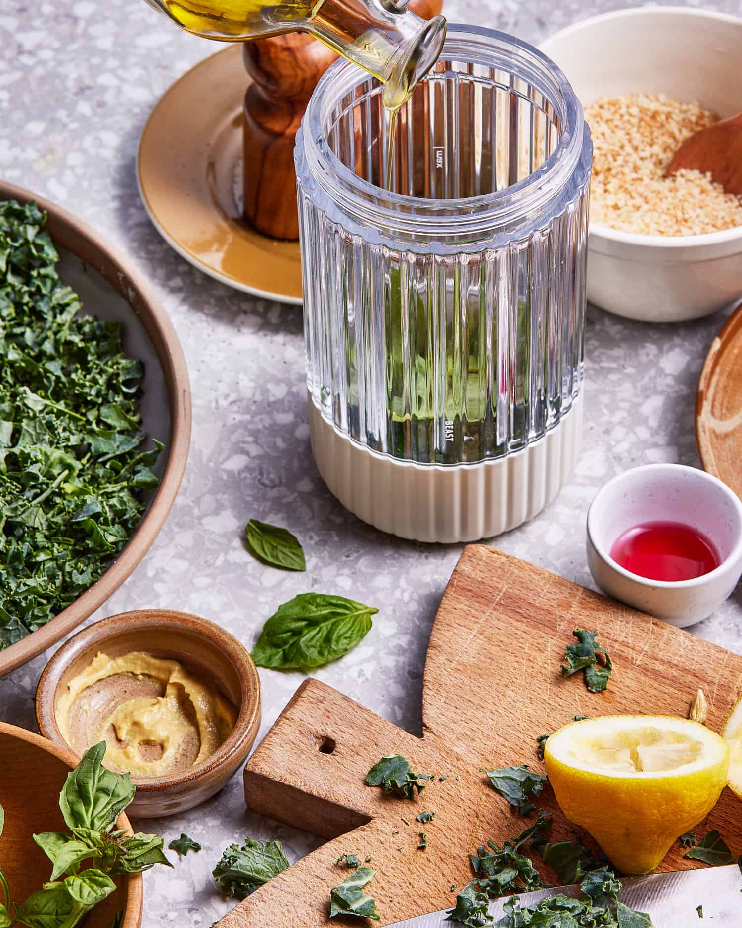 A blender, sitting on a countertop with all of the ingredients needed to make this lemon-basil dressing inside of it