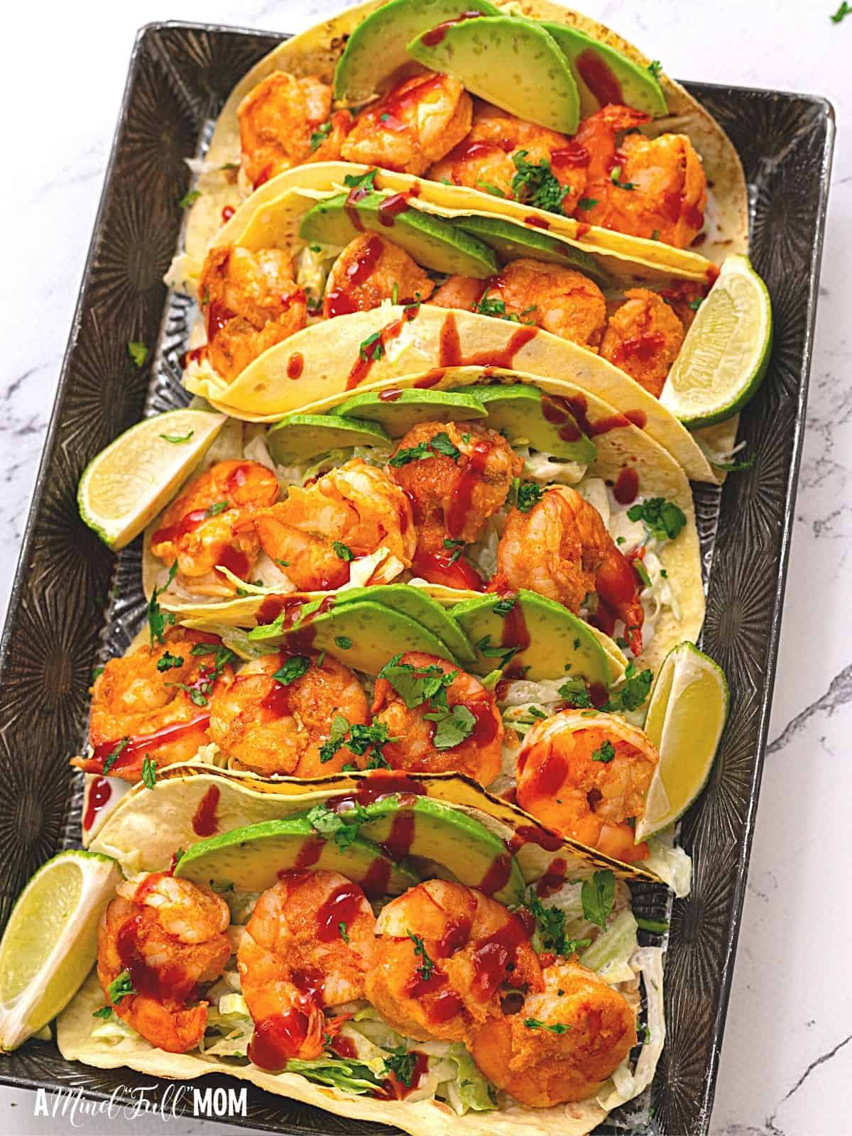 4 assembled shrimp tacos with avocado and slaw. 