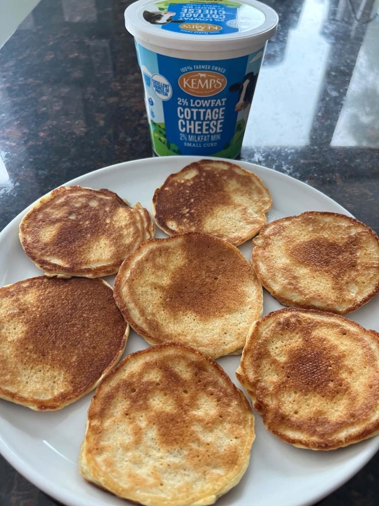 plate of golden brown Cottage Cheese Pancakes next to a container of cottage cheese