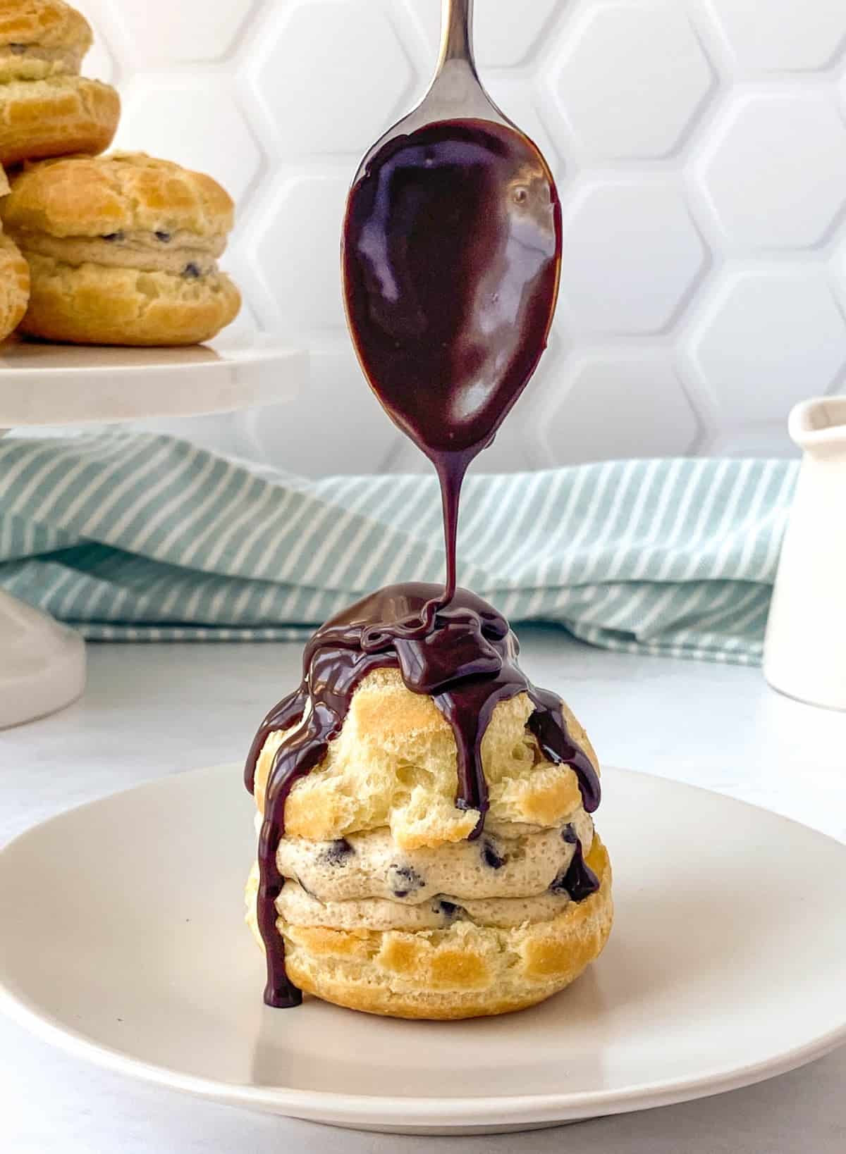 Homemade chocolate sauce being drizzled on a Cookie Dough Cream Puff.
