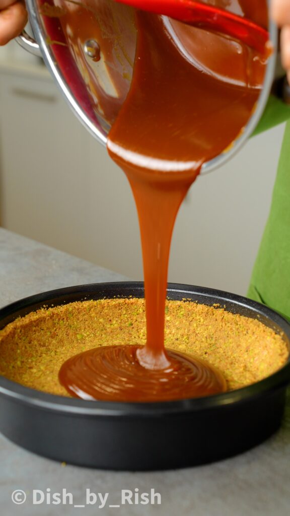pouring caramel into pistachio and biscuit base