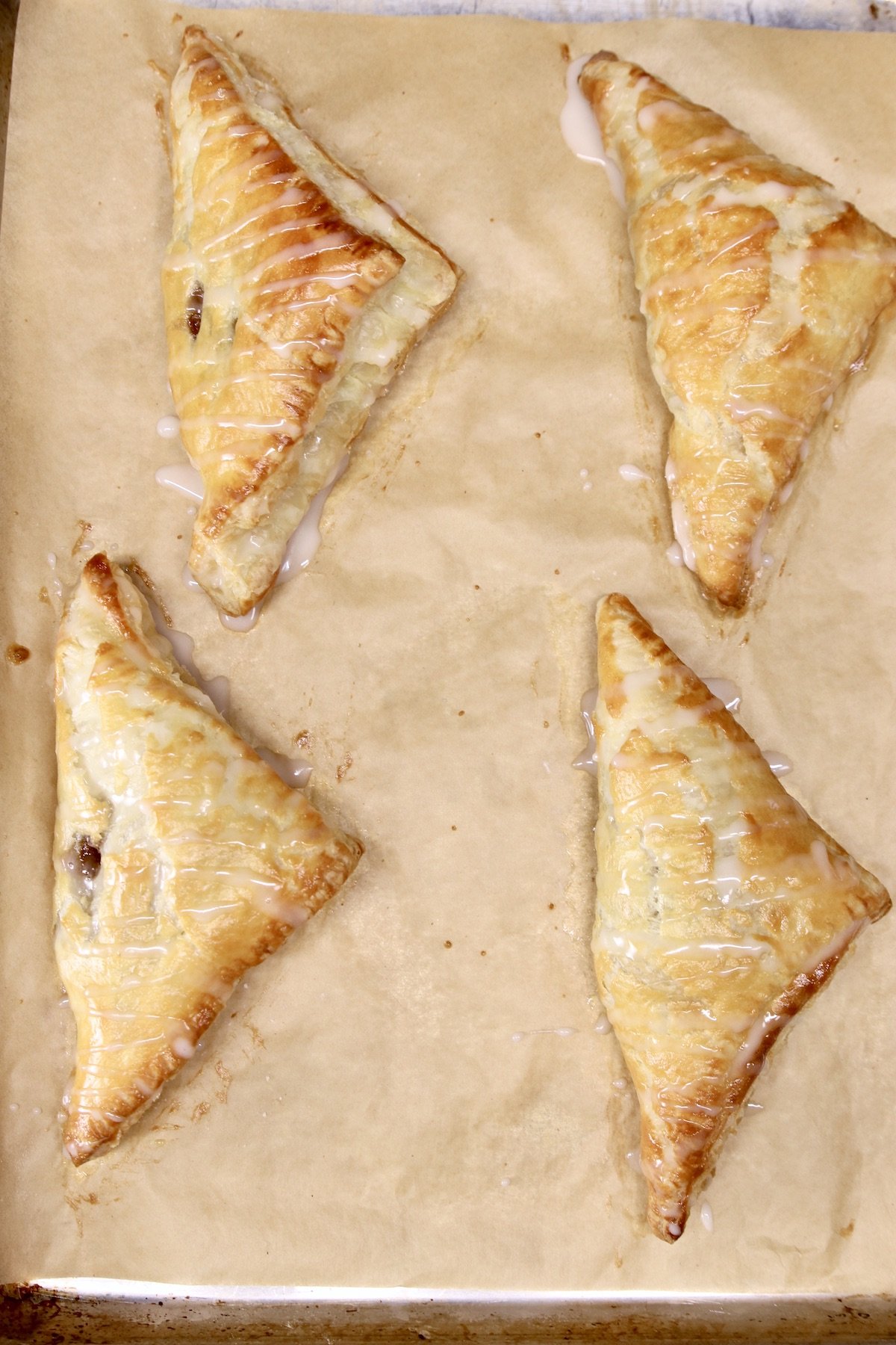 4 baked puff pastry apple turnovers on parchment paper
