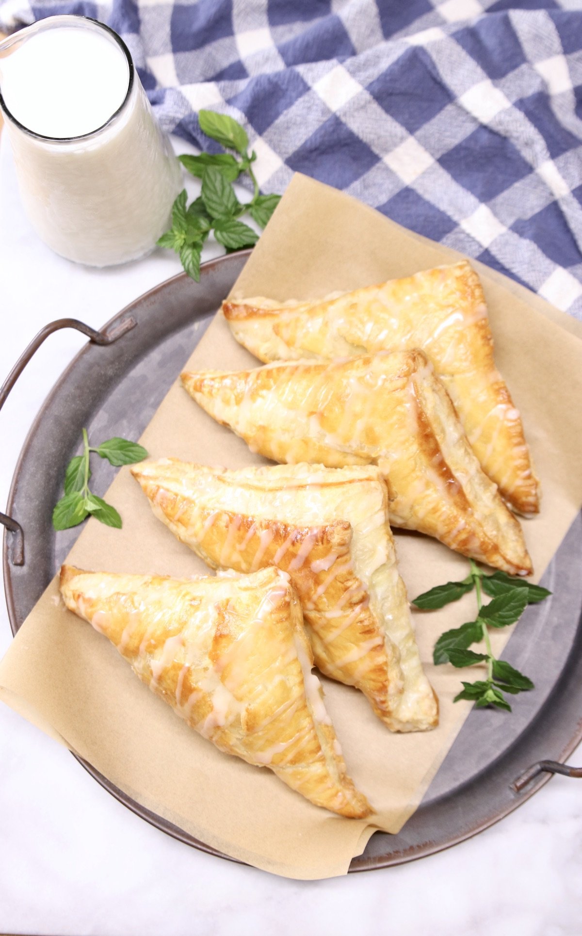 platter of apple turnovers with pitcher of milk, blue napkin