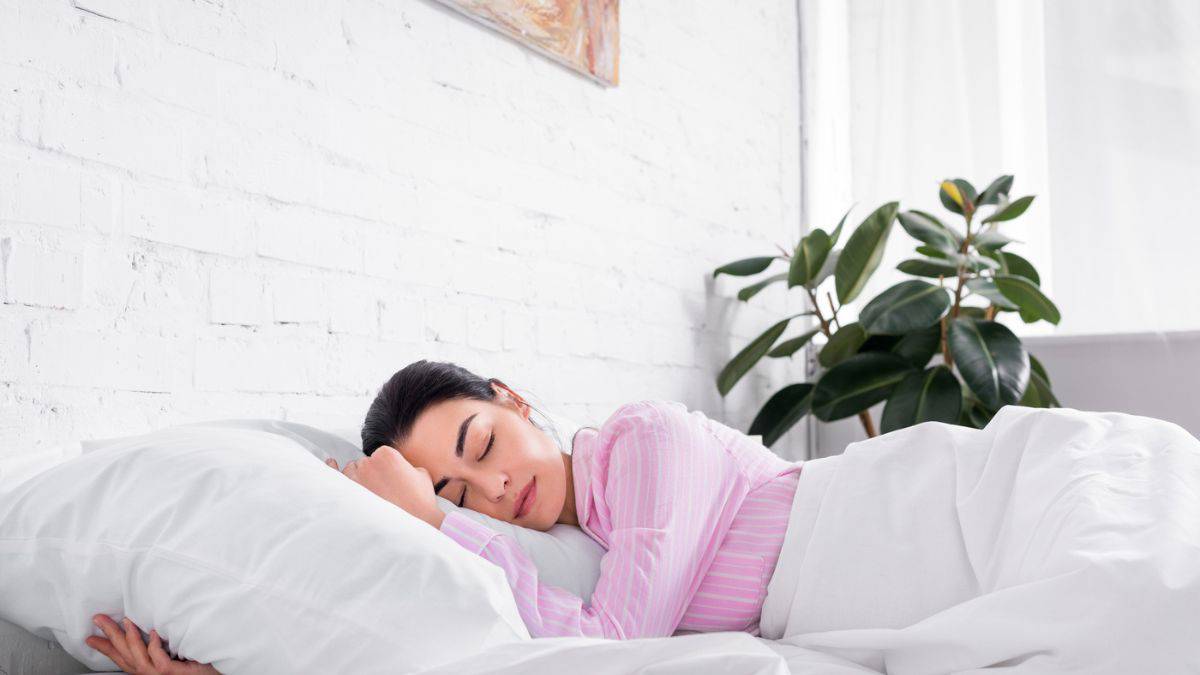 A woman sleeping in a bed with white pillows.