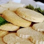 Sugar Cookies on a white plate with rosemary and a sprig of mint